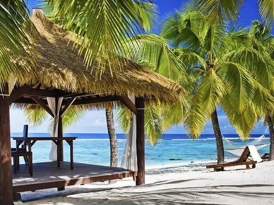 Capanna con tetto di paglia sulla spiaggia tra le palme, Polinesia