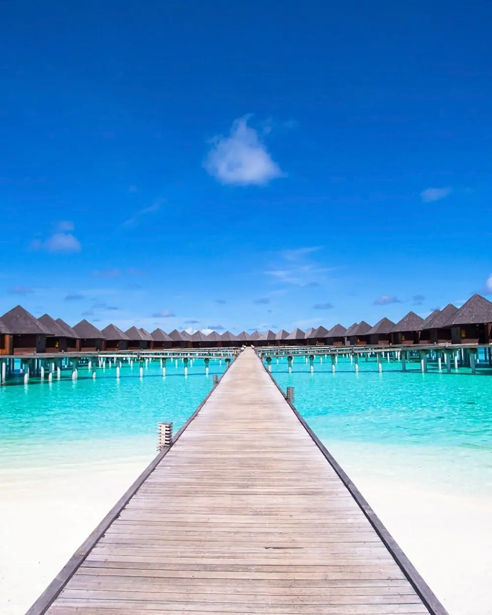Pontile in legno verso le ville sull'acqua in un atollo delle Maldive